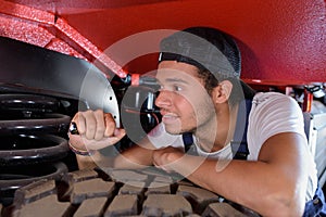 Male mechanic using torch to inspect vehicle