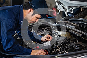 Male mechanics check electrical wiring vehicle system in car service