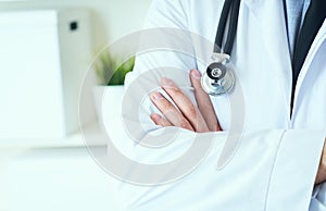 Male medical doctor posing with arms crossed, lab coat, stethoscope and hands close up, healthcare professionals concept
