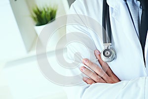 Male medical doctor posing with arms crossed, lab coat, stethoscope and hands close up, healthcare professionals concept