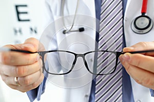 Male medicine doctor hands giving pair of black glasses