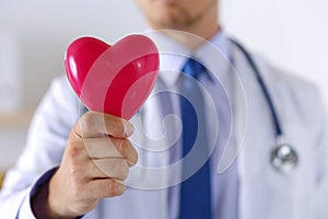 Male medicine doctor hands holding red toy heart