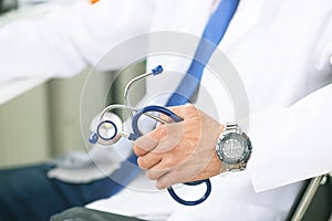 Male medicine therapist doctor hands holding stethoscope in office closeup. Physician is waiting for patient to examine.