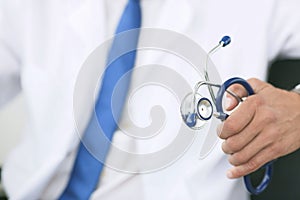 Male medicine therapist doctor hands holding stethoscope in office closeup. Physician is waiting for patient to examine.