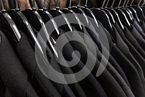 Male Mens Dark Suits on Hangers on a Shop Wardrobe Closet Rail
