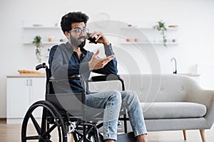 Male with mobility impairment speaking on mobile in kitchen