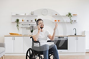 Male with mobility impairment speaking on mobile in kitchen