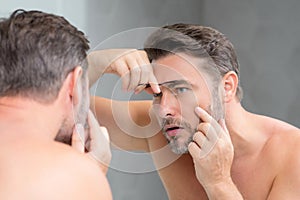 Male model applying cosmetic cream on face. Facial treatment. Beauty portrait of man applying face cream. Skin care