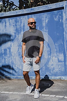 Male model with beard wearing black blank t-shirt on the background of an blue wall