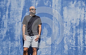 Male model with beard wearing black blank t-shirt on the background of an blue wall