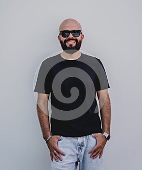 Male model with beard wearing black blank t-shirt on the background of an white wall