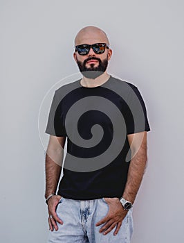 Male model with beard wearing black blank t-shirt on the background of an white wall