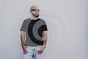 Male model with beard wearing black blank t-shirt on the background of an white wall