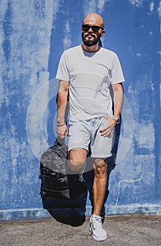 Male model with beard wearing white blank t-shirt on the background of an blue wall