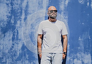 Male model with beard wearing white blank t-shirt on the background of an blue wall