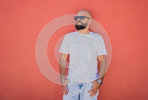 Male model with beard wearing white blank t-shirt on the background of an orange wall