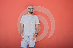 Male model with beard wearing white blank t-shirt on the background of an orange wall