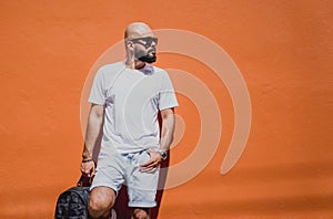 Male model with beard wearing white blank t-shirt on the background of an orange wall