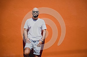 Male model with beard wearing white blank t-shirt on the background of an orange wall