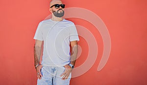 Male model with beard wearing white blank t-shirt on the background of an orange wall