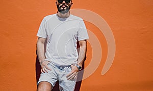 Male model with beard wearing white blank t-shirt on the background of an orange wall