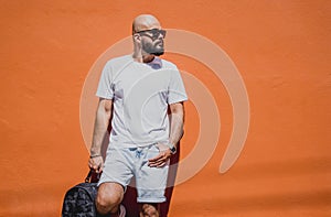 Male model with beard wearing white blank t-shirt on the background of an orange wall