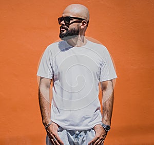 Male model with beard wearing white blank t-shirt on the background of an orange wall