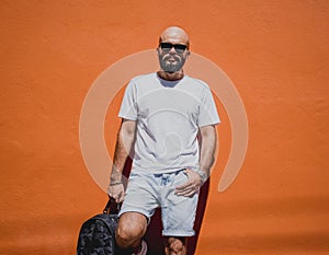 Male model with beard wearing white blank t-shirt on the background of an orange wall