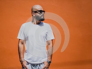 Male model with beard wearing white blank t-shirt on the background of an orange wall