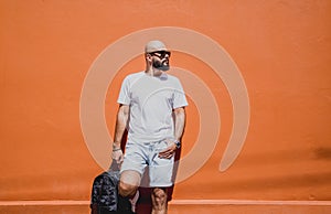 Male model with beard wearing white blank t-shirt on the background of an orange wall