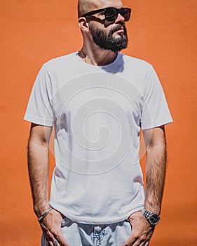 Male model with beard wearing white blank t-shirt on the background of an orange wall