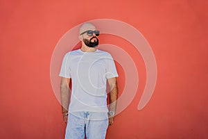 Male model with beard wearing white blank t-shirt on the background of an orange wall