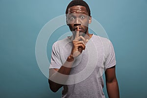 Male model doing hush sign with finger over lips to keep secret