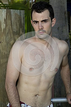 Male model glaring at camera with no shirt wearing swimsui photo