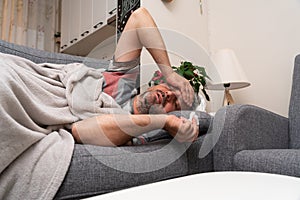 Male model with high fever flu symptoms resting on sofa at home