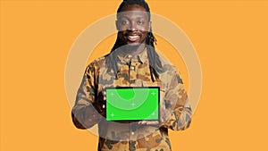 Male model holding laptop with greenscreen layout in studio