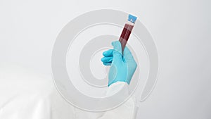 Male model with PPE suite and Hand with glove is holding two blood test tube on white background