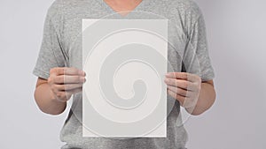 Male model`s hands is holding the A4 paper and wear gray t shirt on white background