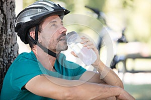 male mountain biker drinking water in forest