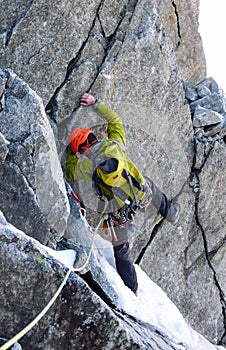 Male mountain climber traverses a tricky rock chimney on his way to a high alpine summit