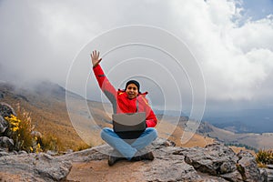 male mountain climber using laptop on mountain peak