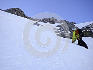 Male mountain guide climbing a steep snow couloir on his way to a high summit in the Swiss Alps