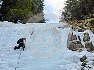 Male mountain guide lead ice climbing a frozen waterfall in deep winter in the Alps of Switzerland