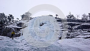 Male mountain guide rappelling off a steep frozen waterfall after an ice climbing excursion