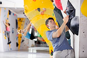 Male mountaineer climbing artificial rock wall without his belay indoors