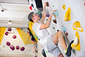 Male mountaineer climbing artificial rock wall without his belay indoors