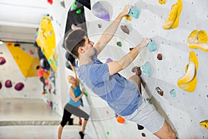 Male mountaineer climbing artificial rock wall without his belay indoors