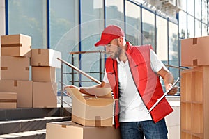 Male mover with clipboard and boxes outdoors