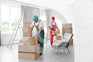 Male movers with boxes in house