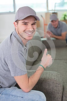 male movers placing sofa on hardwood floor at home